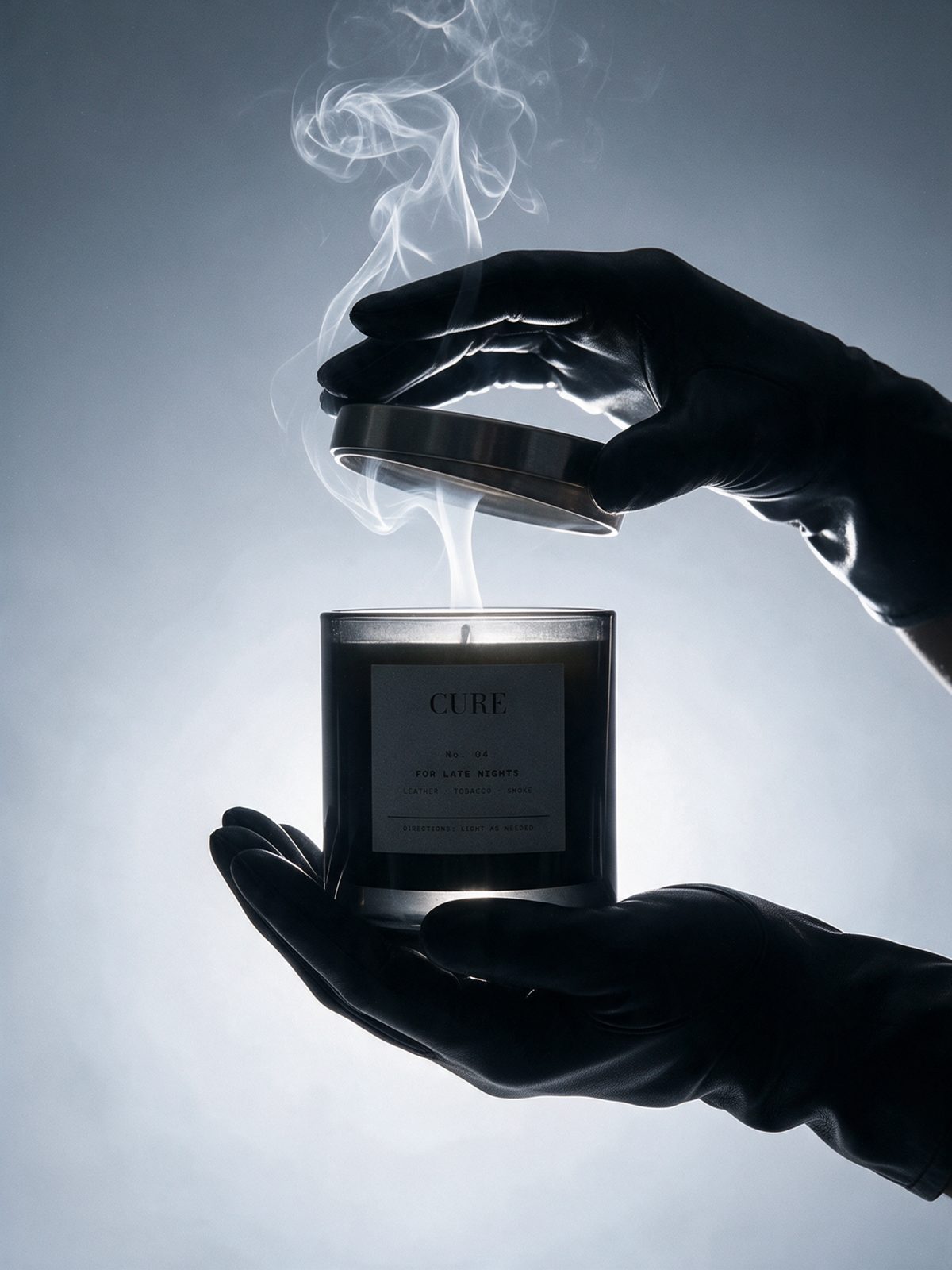 Gloved hands lifting the lid of a CURE candle as smoke rises