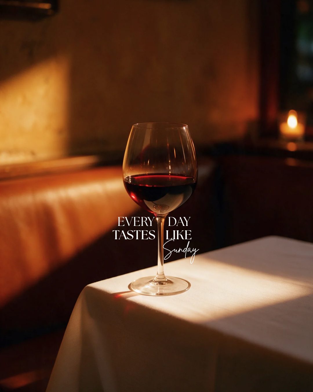 A glass of red wine on a white tablecloth in warm evening light